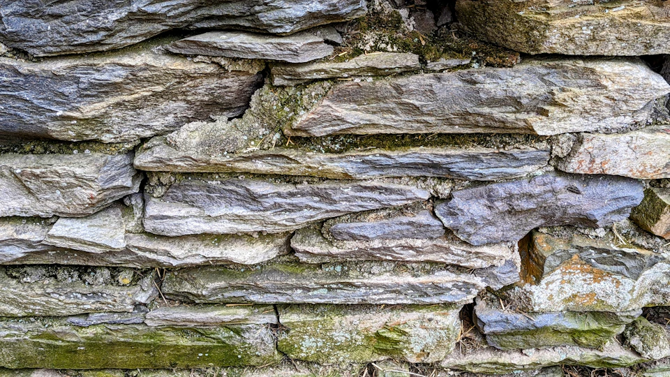 Close-up view of stone wall composed of large, irregularly shaped gray and brown stones
