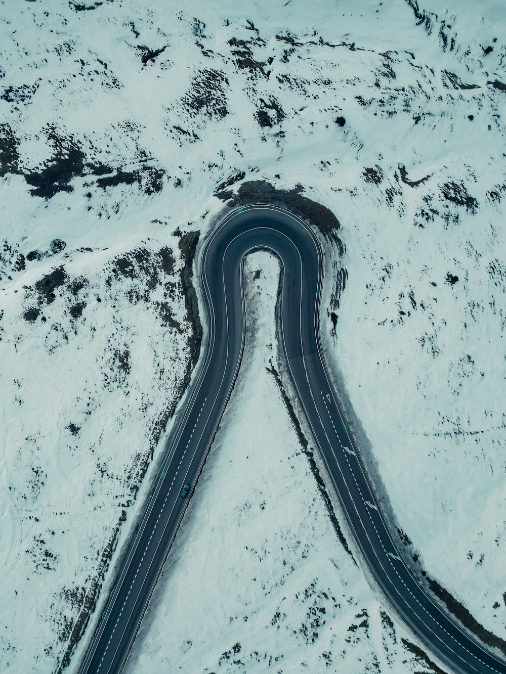 an aerial view of a curved road in the snow