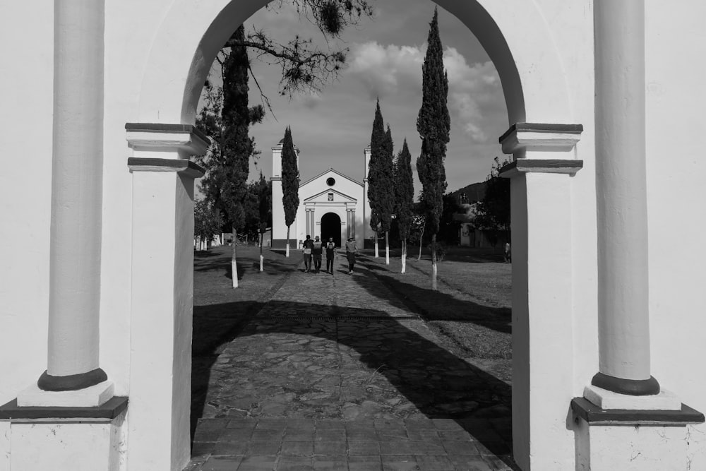 a black and white photo of a church through an arch
