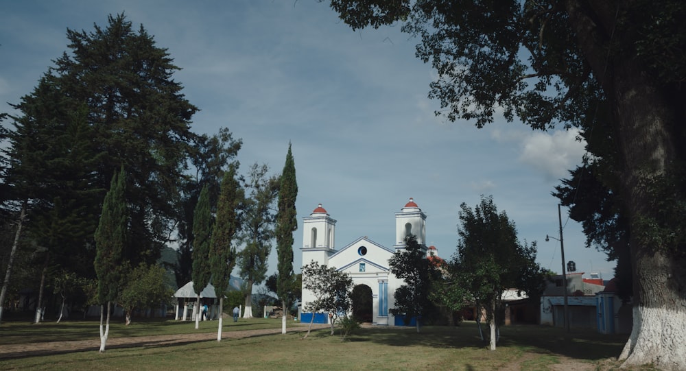 a white church surrounded by trees on a sunny day