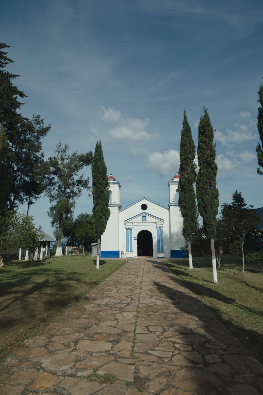 a white church with a blue door on a dirt road