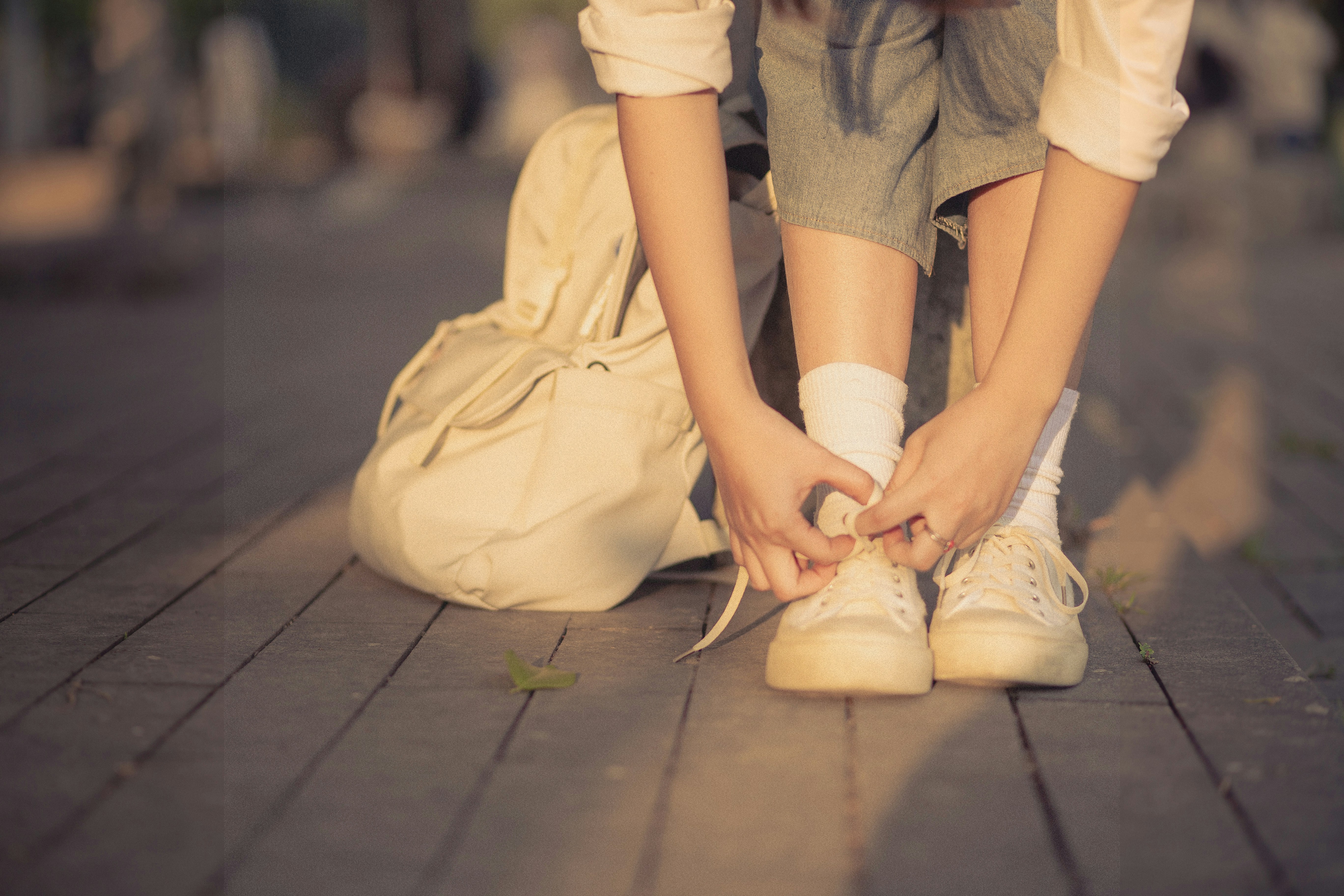 a woman tying her shoes on the sidewalk