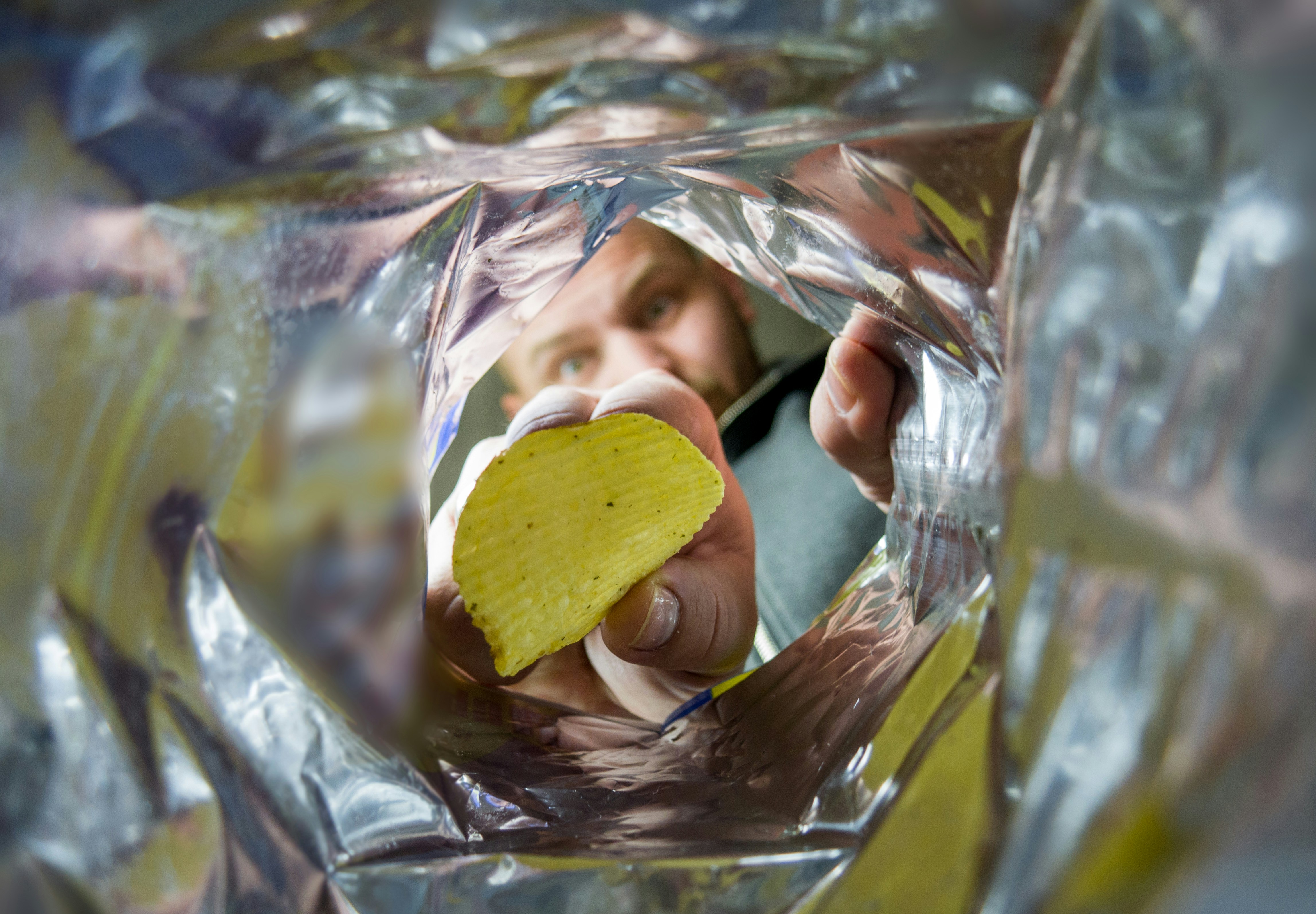 a man holding a cell phone and a potato chip in his hand