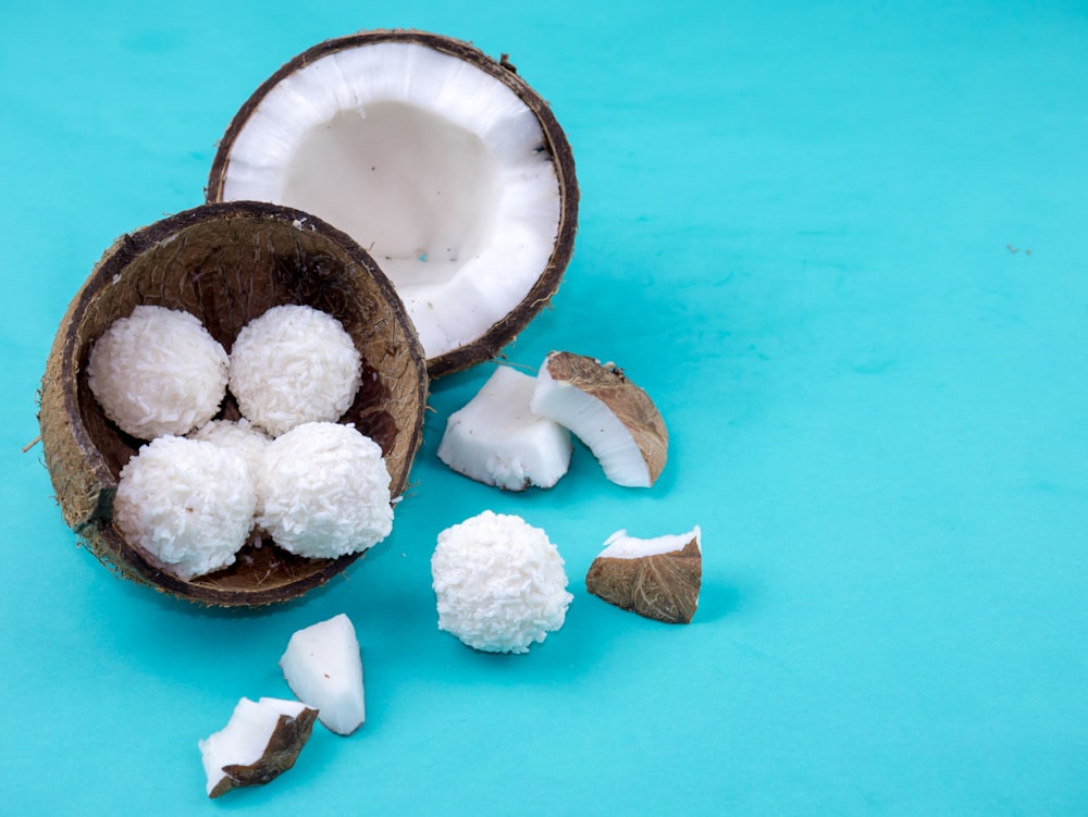 un coco a medio comer y trozos de coco sobre un fondo azul