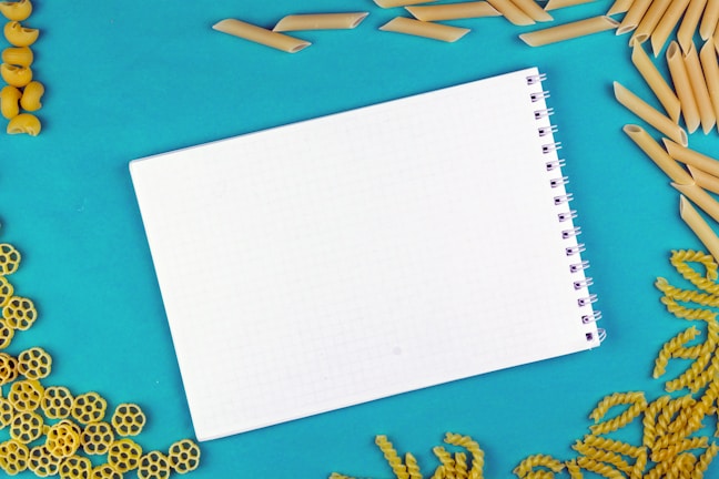 An overhead view of a meal plan notebook surrounded by healthy pizza ingredients.