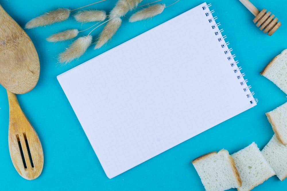 a notepad, wooden spoons, and a wooden spatula on a blue