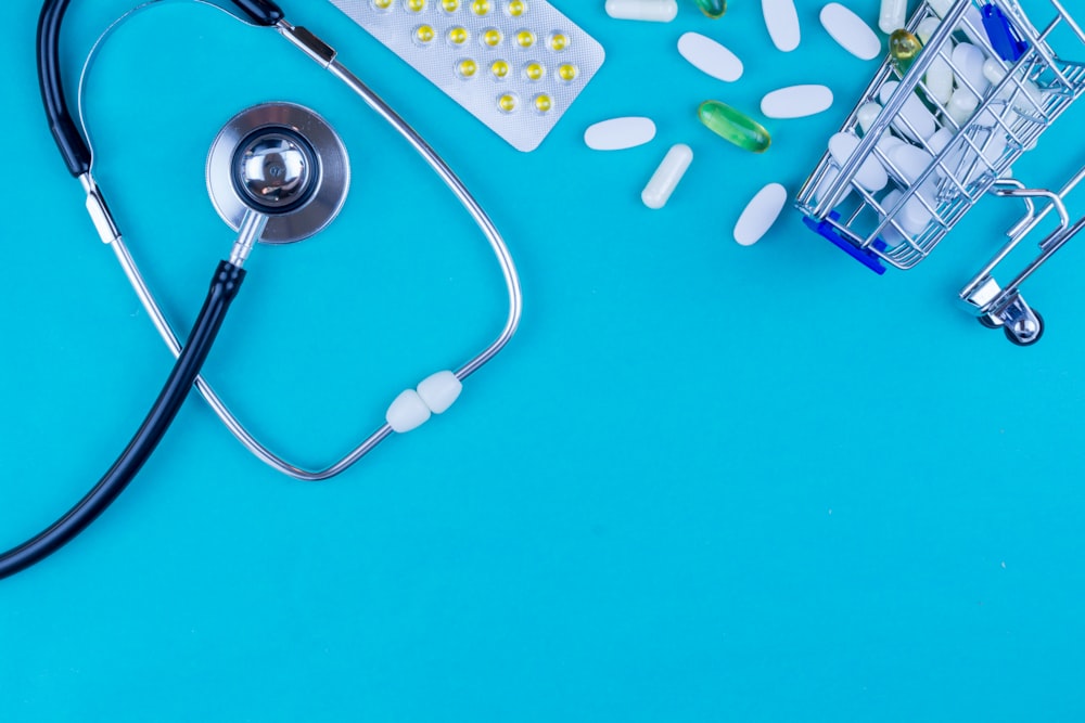 a stethoscope, pills, and a shopping cart on a blue background