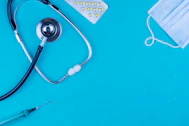 a stethoscope, a medical mask, and a pen on a blue