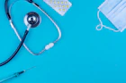 a stethoscope, a medical mask, and a pen on a blue