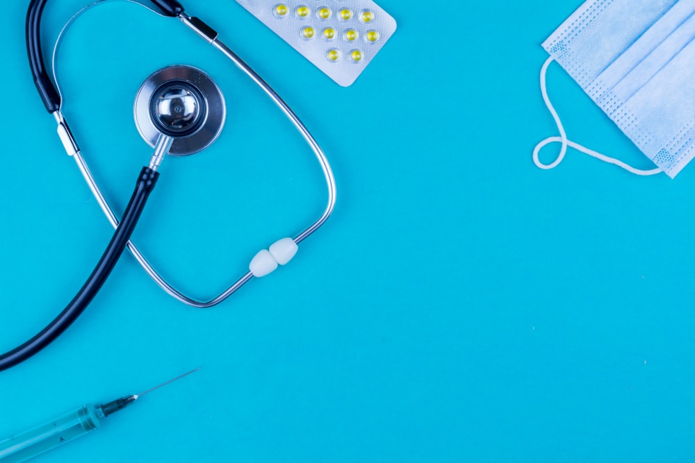 a stethoscope, a medical mask, and a pen on a blue