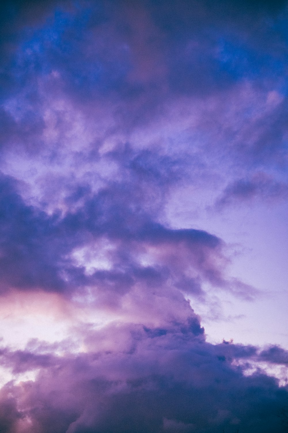 a plane flying through a cloudy blue sky