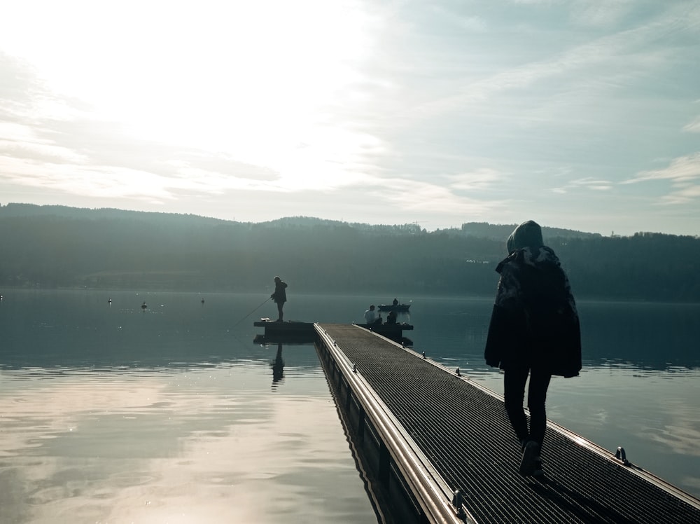 a person standing on a dock next to a body of water