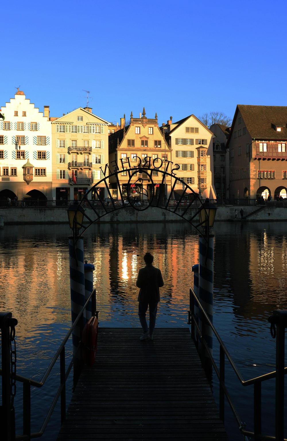 a man walking across a bridge over a body of water