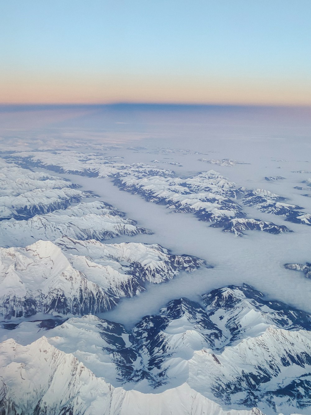 an aerial view of snow covered mountains and valleys
