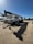 A large white truck crane with the brand name 'Terex' is parked in a construction yard. The crane is aligned with several other construction vehicles, and a bright blue sky is visible in the background. Shadows from the crane are cast prominently on the ground.