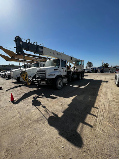 Technician inspecting a Titan hydraulic crane mounted on a truck under a bright sky.