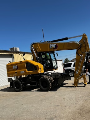 A friendly TJ Land Services team member standing next to a mini excavator on a sunny day in York, PA.