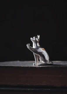 A whimsical resin sculpture of a cat curled up on a tiny, detailed vintage book.