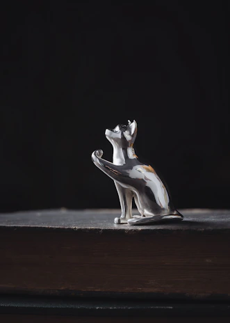 A whimsical resin sculpture of a cat curled up on a tiny, detailed vintage book.