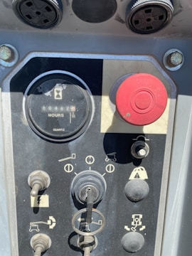 A control panel featuring various switches and knobs, a key inserted into a central lock, and an hour meter displaying 48.2 hours. There is a prominent red button and multiple symbols indicating the functions of the controls.