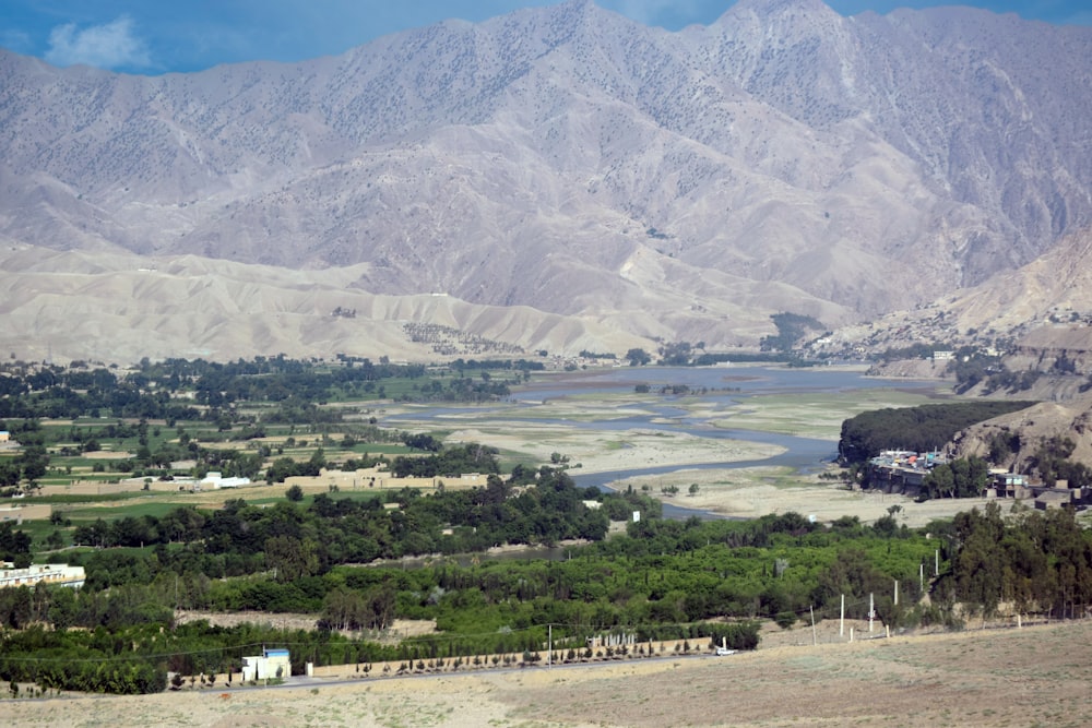 a scenic view of a valley with a lake and mountains in the background