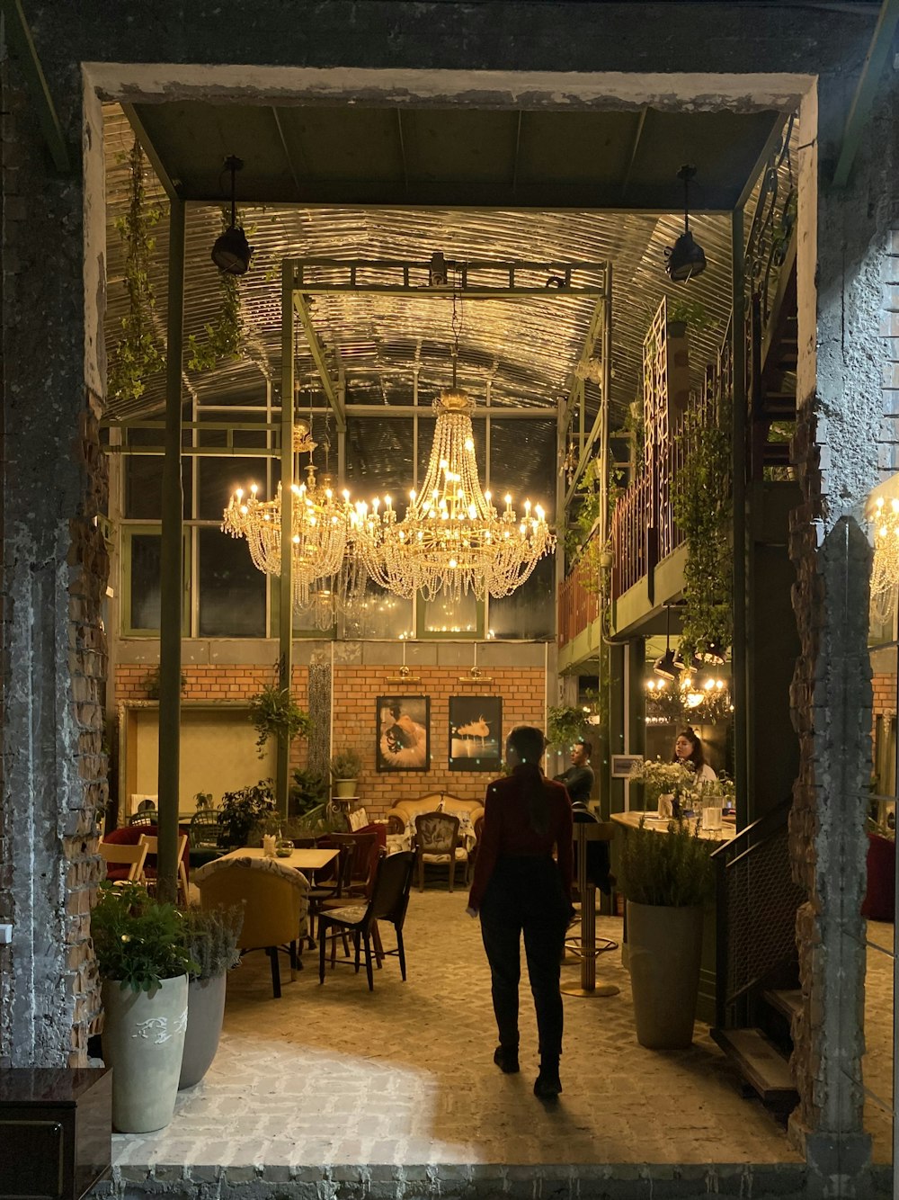 a person walking into a restaurant with a chandelier hanging from the ceiling