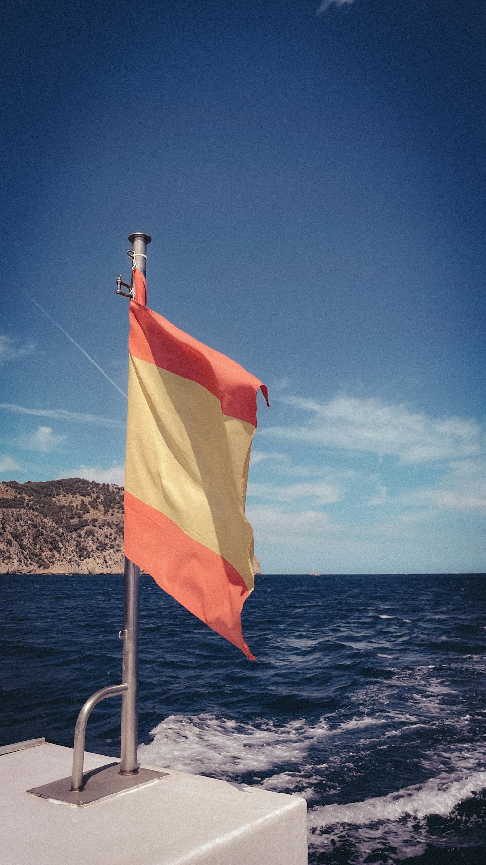 an orange and yellow flag on a boat in the ocean