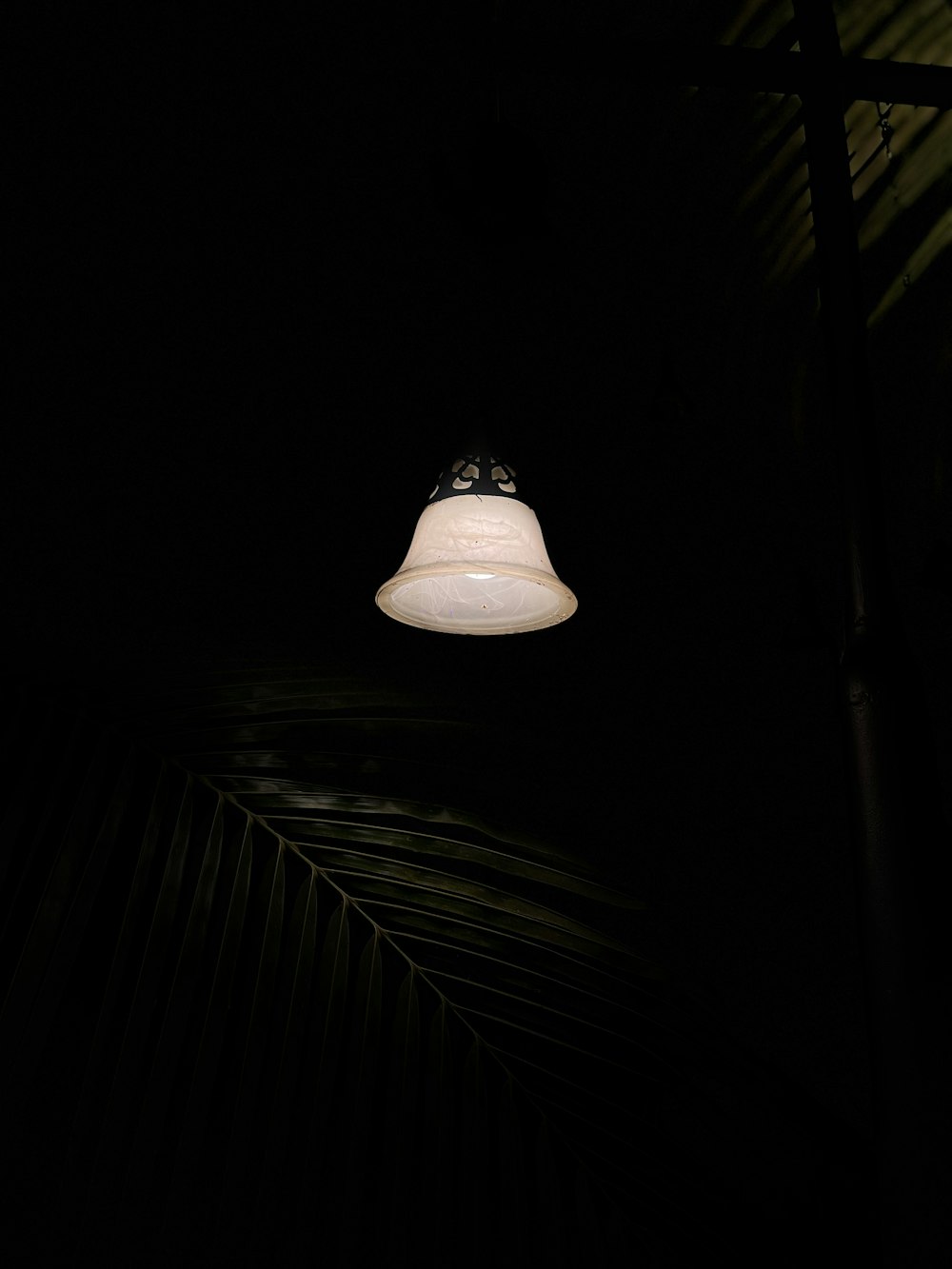a white light hanging from a ceiling in a dark room