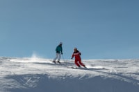 A couple of people riding skis down a snow covered slope