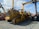 A lineup of heavy construction machinery, including large bulldozers and other vehicles, set on a gravel surface. The equipment features prominent treads and metal arms, indicating their use for construction and heavy-duty tasks.