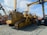 A lineup of heavy construction machinery, including large bulldozers and other vehicles, set on a gravel surface. The equipment features prominent treads and metal arms, indicating their use for construction and heavy-duty tasks.