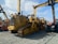 A lineup of heavy construction machinery, including large bulldozers and other vehicles, set on a gravel surface. The equipment features prominent treads and metal arms, indicating their use for construction and heavy-duty tasks.