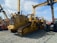 A lineup of heavy construction machinery, including large bulldozers and other vehicles, set on a gravel surface. The equipment features prominent treads and metal arms, indicating their use for construction and heavy-duty tasks.