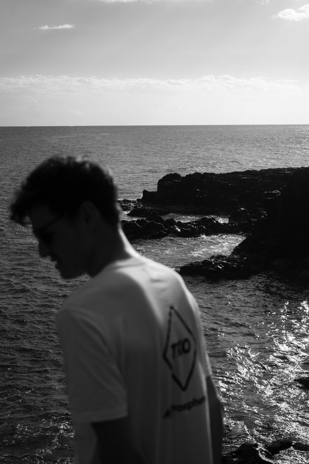 a man standing on top of a rocky beach next to the ocean