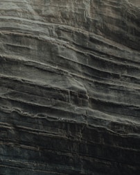 Layers of sedimentary rock are stacked unevenly, showcasing the natural textures and formations typical of eroded cliff faces. The surface appears rugged and weathered, indicative of geological processes over time.