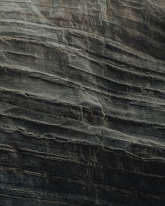 Layers of sedimentary rock are stacked unevenly, showcasing the natural textures and formations typical of eroded cliff faces. The surface appears rugged and weathered, indicative of geological processes over time.