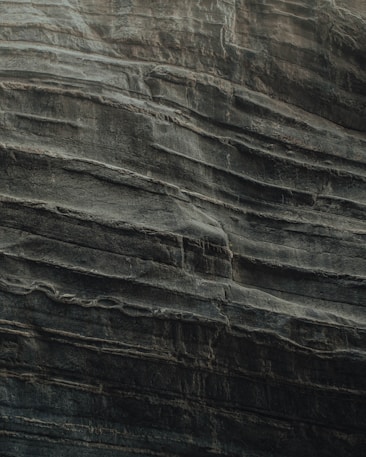 Layers of sedimentary rock are stacked unevenly, showcasing the natural textures and formations typical of eroded cliff faces. The surface appears rugged and weathered, indicative of geological processes over time.