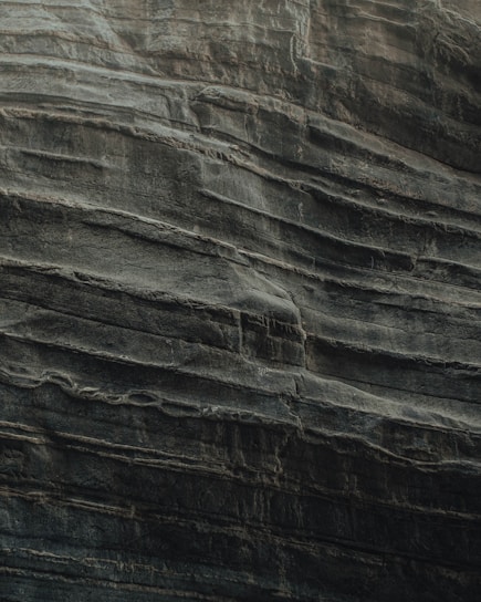 Layers of sedimentary rock are stacked unevenly, showcasing the natural textures and formations typical of eroded cliff faces. The surface appears rugged and weathered, indicative of geological processes over time.
