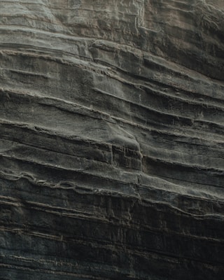 Layers of sedimentary rock are stacked unevenly, showcasing the natural textures and formations typical of eroded cliff faces. The surface appears rugged and weathered, indicative of geological processes over time.