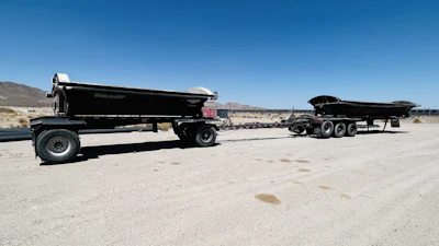 A rugged oilfield trailer parked on dusty Texas terrain under a wide blue sky.
