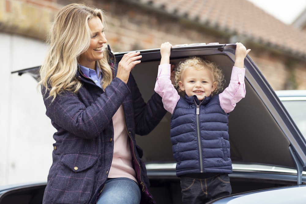 a woman holding a child's suitcase in the back of a car