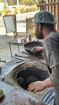 Chef preparing fresh naan bread in a traditional tandoor oven.