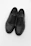 Close-up of a stylish black leather men's shoe on a white background with subtle gold accents.