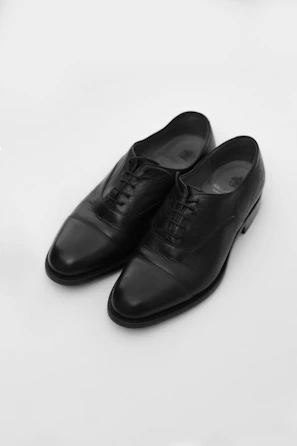 Formal shoes polished to a shine, displayed on a minimalist black surface.