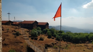 a red flag on top of a hill next to a building