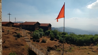 a red flag on top of a hill next to a building