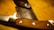 A close-up view of a finely crafted knife with a wooden handle lying beside a leather sheath, which has the brand name and logo embossed on it. The blade appears sharp and well-polished, and the leather is stitched with precision.