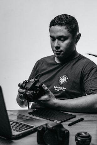 A focused creator working on a laptop surrounded by camera gear and notes.