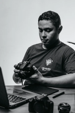 A candid photo of Adrian Vale working at his desk surrounded by video equipment and creative notes.