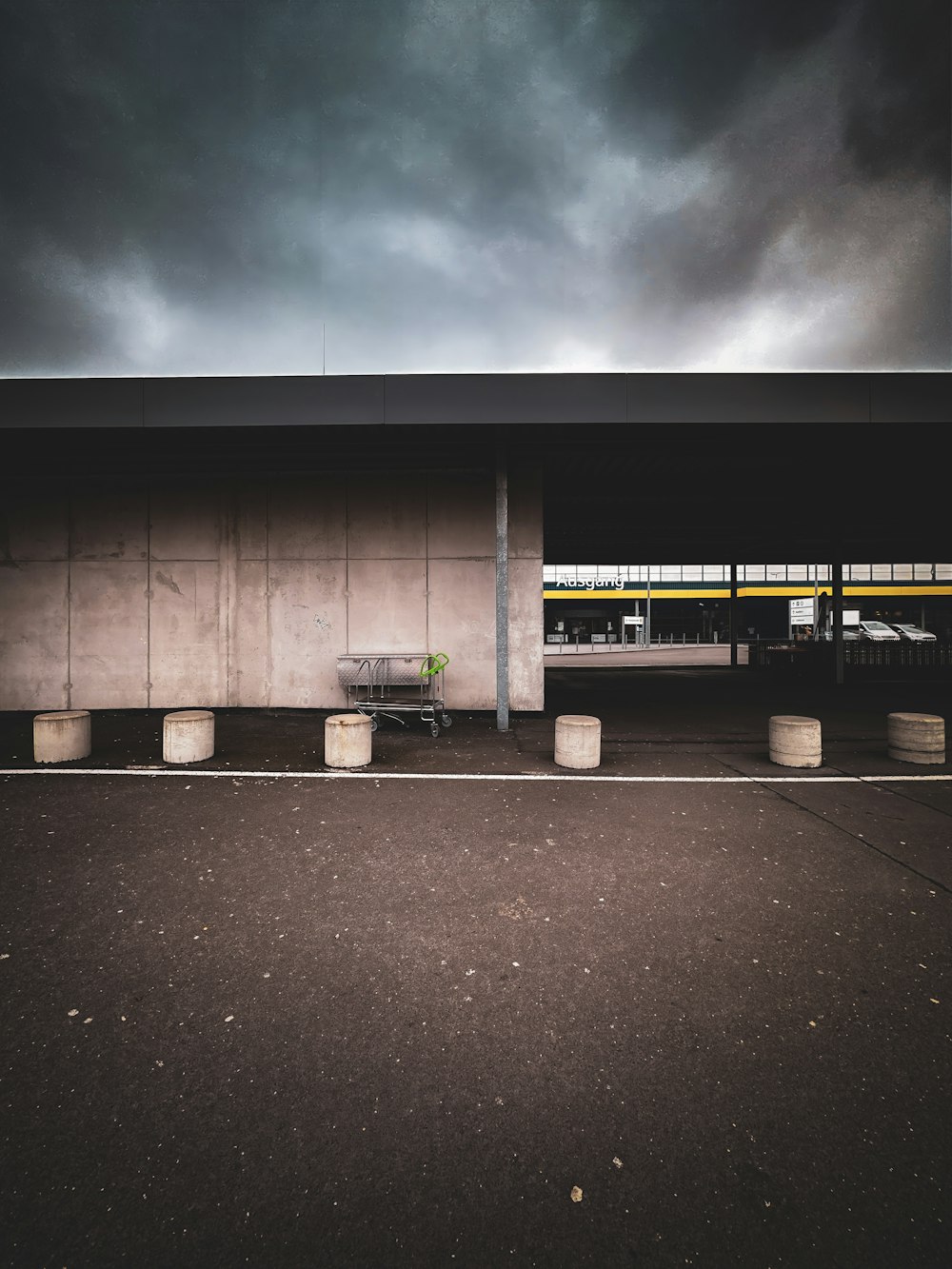 an empty parking lot with a bench under a cloudy sky